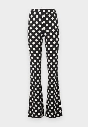 Svarte vide bukser med store hvite polkadotter og elastisk midje, vist mot en enkel lys bakgrunn.