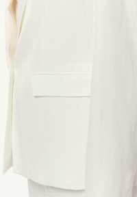 Weißer Blazer mit glatter Textur, ausgestattet mit einer einzelnen, flachen Tasche auf der rechten Seite, strukturiertem Design und taillierter Passform.