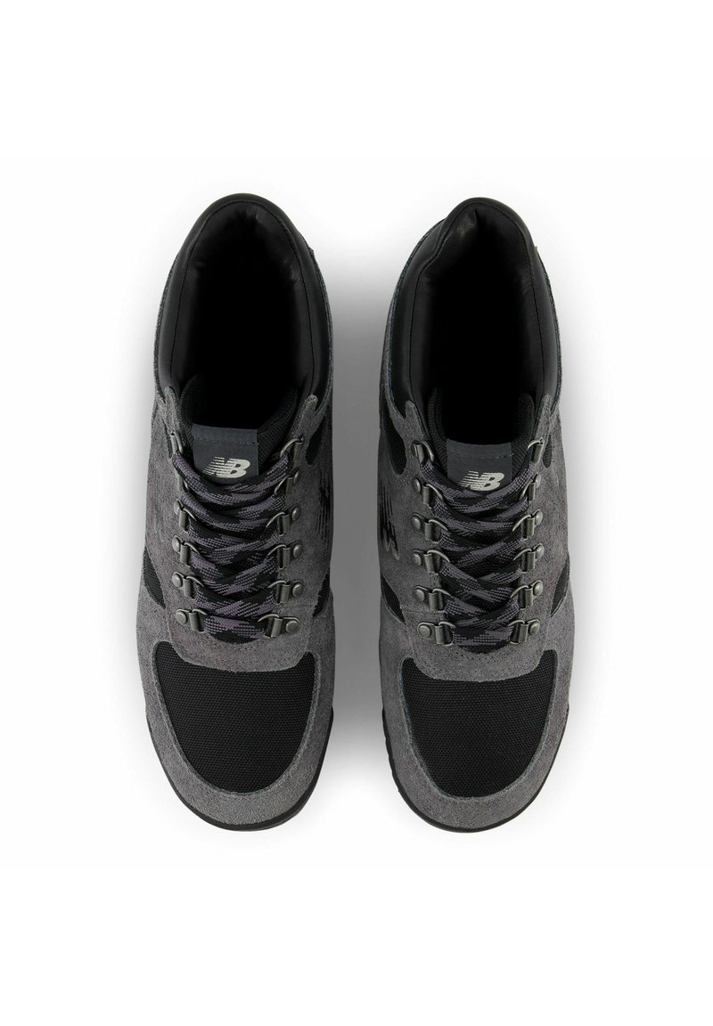 Baskets de sport en daim gris et maille avec des accents noirs, dotées d'œillets en métal, de lacets texturés et d'un design à bout rond.