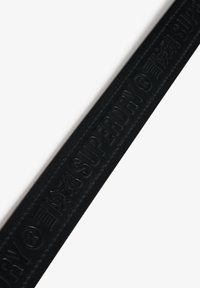 Czarny kauczukowy pasek o podniesionej teksturze z logo "SUPERDRY". Gładkie wykończenie i lekki połysk; przeszywane krawędzie zwiększają trwałość.