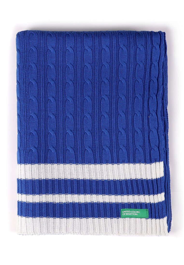 Blauwe gebreide dekentje met een kabelpatroon en witte strepen aan de onderkant. Bevat een groen label met "United Colors of Benetton."