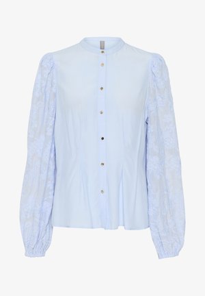 Svetlo modra bluza s gumbom spredaj, zložena zasnova in dolgi pufasti rokavi z vezenimi cvetličnimi detajli. Gladka tekstura tkanine.