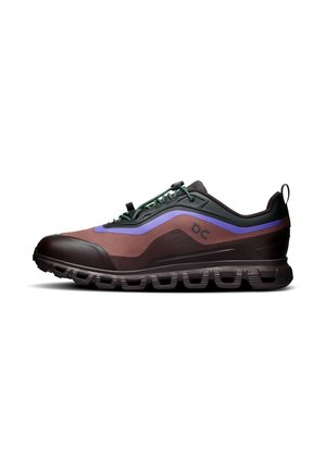 Chaussure de sport profil bas marron avec semelle noire, bande d'accent violet, lacets verts et col rembourré vue de côté sur fond blanc.