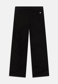 Pantalons larges noirs avec une ceinture élastique. Matière en coton doux, avec une poche arrière portant un petit écusson logo.