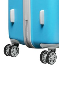 Harde blauwe koffer met een gestructureerd oppervlak, zilverkleurige rits en vier 360-graden draaibare wielen voor mobiliteit. De zijhandvatten zijn wit.