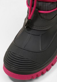 Botte imperméable noire et rose avec une semelle en caoutchouc texturé, une tige lisse et des lacets roses ajustables avec un système de fermeture à bascule noir.