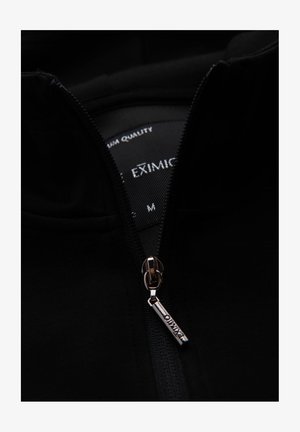 Zwarte zip-up jack van gladde stof, uitgerust met een metalen rits met een merkembleem en een binnenlabel met maat M.