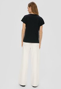 Czarny t-shirt z krótkim rękawem i okrągłym dekoltem, połączony z białymi spodniami z szerokimi nogawkami i wysokim stanem. Prosty, casualowy design bez wzorów.