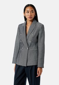 Blazer à rayures double boutonnage en noir et blanc. Présente un col cranté, des détails de boutons et des poches avant avec un passepoil contrasté.