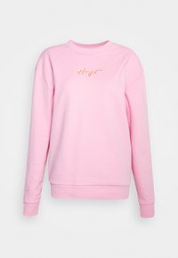 Roze sweatshirt van zachte stof, met een ronde hals, doorgezakte schouders en geborduurde "Hugs" in gouden letters op de voorkant.