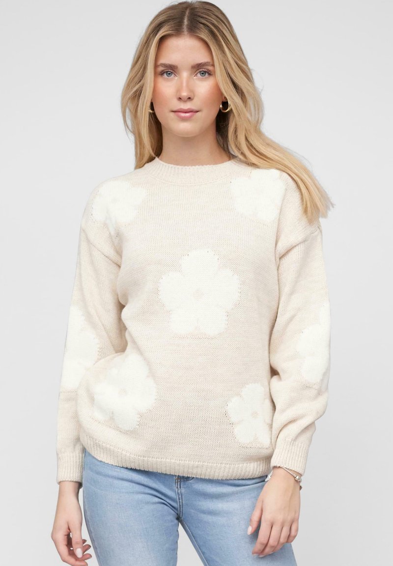 Beige gestrickter Pullover mit großen weißen Blumenmustern, Rundhalsausschnitt und gerippten Bündchen. Glatte Textur und lockere Passform.