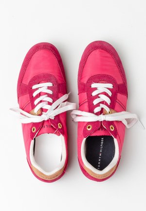 Para czerwonych i różowych sneakersów z białymi sznurówkami i brązowymi akcentami na obcasie, widziana z góry na białym tle.