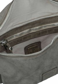 Interno di una borsa in pelle grigia con foderatura in tessuto chiaro, numerosi scomparti con cerniera e un dettaglio superficiale testurizzato.