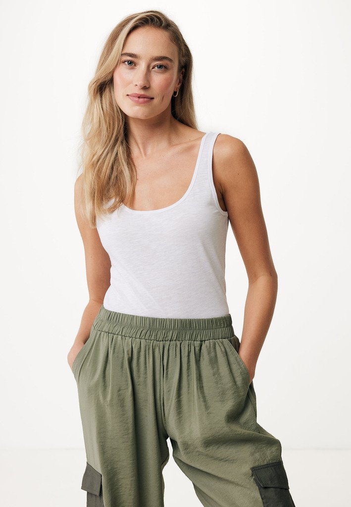 Top in cotone bianco a canotta abbinato a pantaloni cargo verdi, larghi, con vita elastica, dotati di tasche laterali e una finitura testurizzata.
