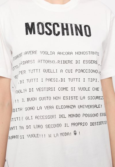 T-shirt en coton blanc avec du texte imprimé en noir dans des polices variées. Le nom de la marque "MOSCHINO" en haut, avec une typographie stylisée tout au long.