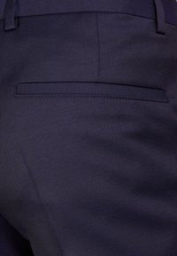 Mörkblå kostymbyxor med en slät yta, som har en bakficka med en diskret söm och en klassisk skräddarsydd design.