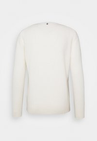 Maglione bianco realizzato in morbido materiale, con maniche lunghe, scollatura rotonda e polsini e orlo a coste. C'è un piccolo logo sul retro.