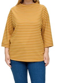 Mosterdgeel gestreept topje met witte lijnen, voorzien van een ronde hals en driekwart mouwen, gecombineerd met blauwe spijkerbroek.