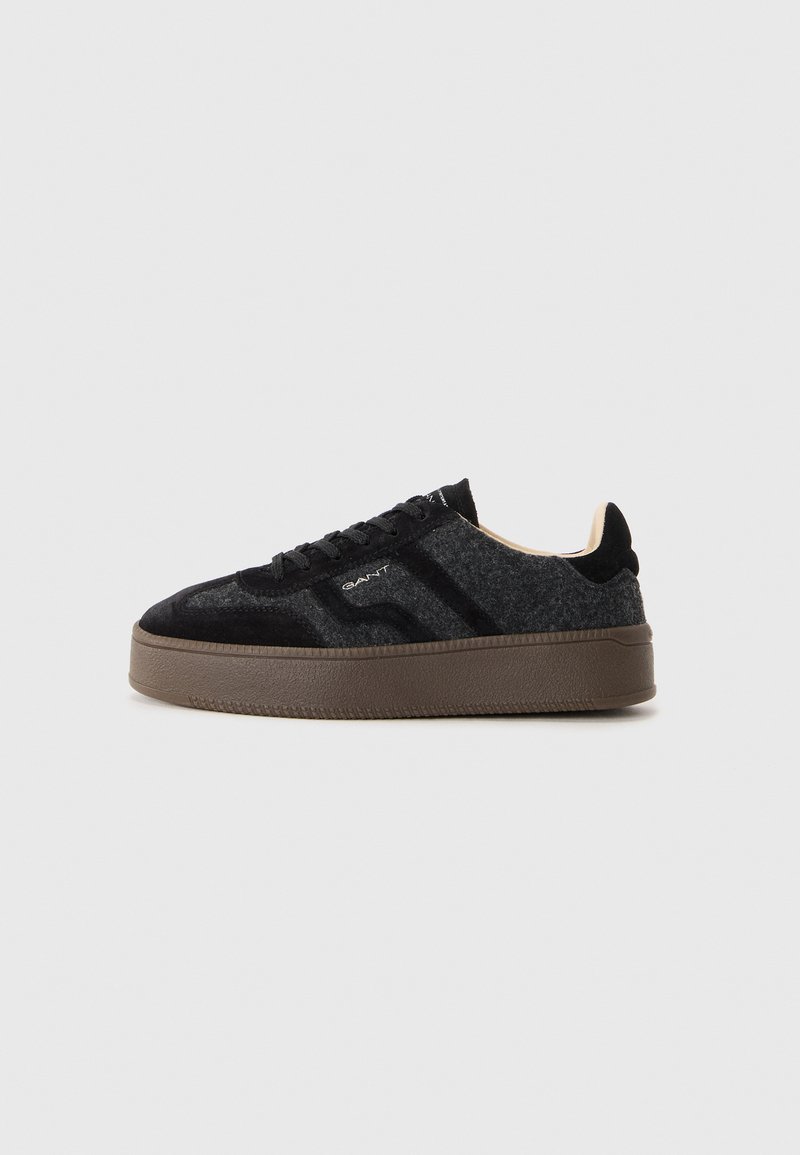 Zapatillas con una textura negra y gris, con parte superior de ante, punta redonda, diseño de cordones y una gruesa suela de goma marrón.