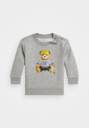 Sweatshirt cinza com uma ilustração de um urso a usar uma camisa e um boné, acompanhado de calções verdes. Inclui detalhes em botão no ombro.