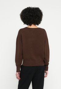 Καφέ πουλόβερ πλεκτό με μακριά μανίκια, στρογγυλή λαιμόκοψη και ριμπ τελείωμα. Ομαλή υφή, άνετη εφαρμογή και διακριτικές λεπτομέρειες ραφής.