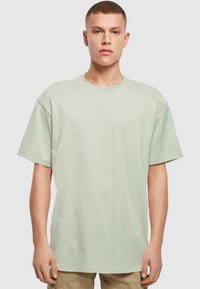 Lys grøn, oversized bomulds t-shirt med korte ærmer og rund halsudskæring. Glat tekstur, ingen synlige mønstre eller detaljer.