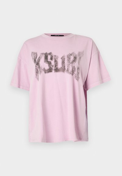 Gaiši rozā pārāk liela T-kreklu ar īsām piedurknēm un apaļu kakla izgriezumu. Priekšpusē ir liels melns grafiskais prints ar vārdu "KSUBI".