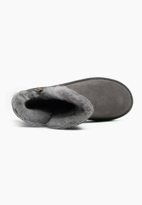 Botín de ante gris con un suave forro de piel de oveja gris. Presenta una punta redondeada y suela plana. Incluye un pequeño acento decorativo de metal.