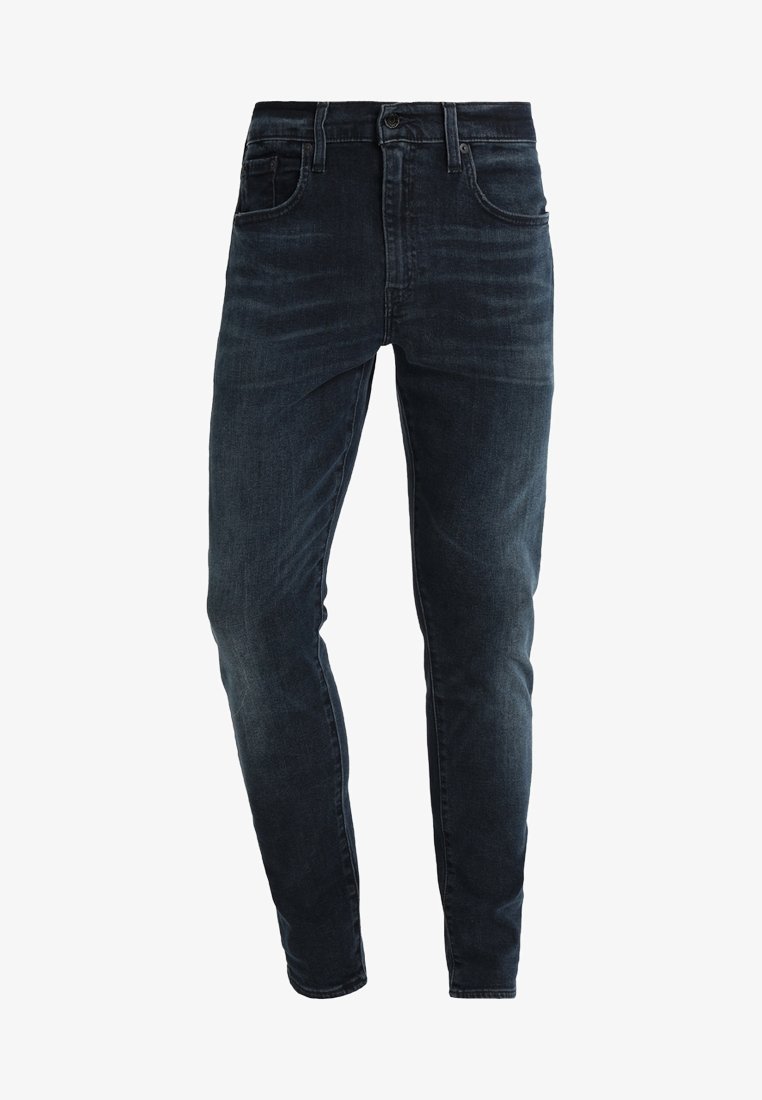 Jean slim bleu foncé avec poches avant et arrière, passants pour ceinture et fermeture par bouton.