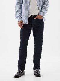 Vaqueros de mezclilla azul oscuro con un corte recto, que cuentan con cinco bolsillos y detalles de costura, combinados con una camisa de botones de rayas claras.