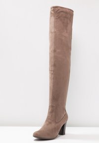 Botas de ante color topo hasta la rodilla con acabado texturizado, punta estrecha y tacón de bloque robusto. Presentan un diseño sin costuras ni adornos.