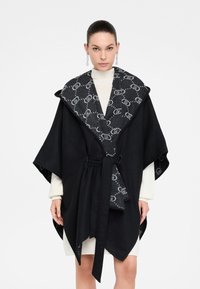 Poncho nero con ampio colletto e vita cinturata, caratterizzato da una fodera a motivo antracite. Realizzato in misto lana, con una consistenza morbida.