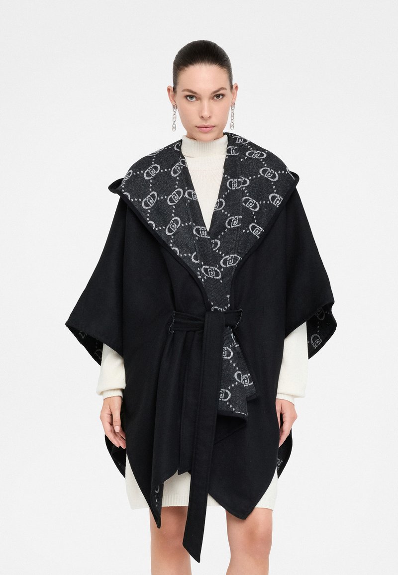 Poncho nero con ampio colletto e vita cinturata, caratterizzato da una fodera a motivo antracite. Realizzato in misto lana, con una consistenza morbida.