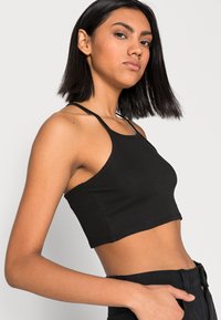 Top crop preto com nervuras, de corte justo, com alças finas e um design limpo. O material parece ser suave e elástico.