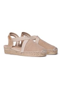 Beige kanva espadriller med kryssede stropper, juteinnviklede kilehæler og stingdetaljer. Lett og åpen hældesign.