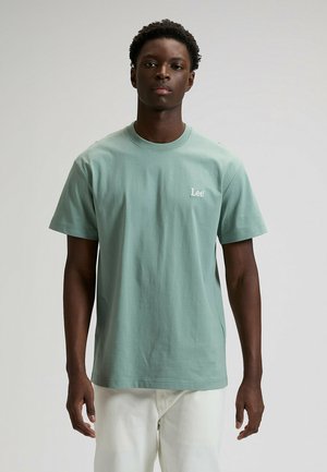 Lysegrøn bomulds-T-shirt med korte ærmer, rund halsudskæring og hvidt "Lee"-logo på øverste venstre side. Glat tekstur, afslappet pasform.