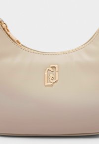 Borsa in ecopelle beige con una texture liscia, forma curva, accessori in tonalità oro e un logo accentuato sul davanti. Chiusura con zip nella parte superiore.