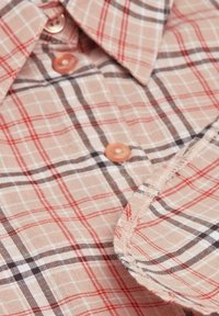 Karierter Hemd mit einem hellbraunen Grundton, roten und dunkelbraunen Linien, Kragen und Kunststoffknöpfen in passenden Farben.