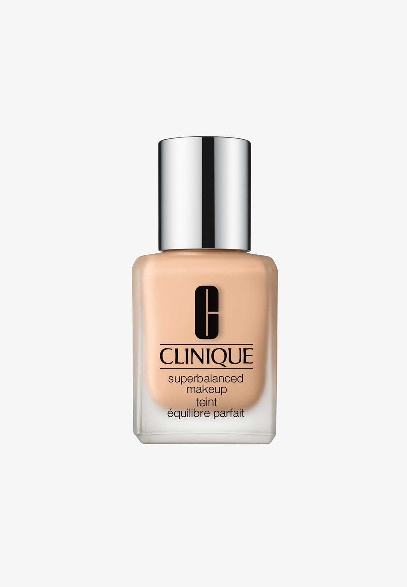 CLINIQUE Maquillaje Superbalanced en un frasco de vidrio transparente, presenta un líquido beige mate con una tapa plateada y un logotipo negro llamativo.