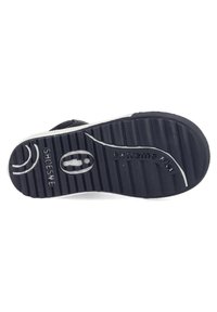 Zwarte rubberen zool met horizontale groeven, "Extreme Flex" merknaam, cirkelvormig logo-detail en een gladde witte randaccent.