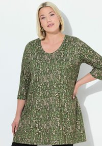 Groene tuniek met een ronde hals, driekwart mouwen en een decoratief patroon van lichte en donkere vormen. Zachte stof met een ontspannen pasvorm.