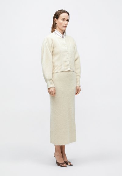 Elevandiluunvalge villa segu kardigan nööpidega ja soonikkoes detailidega, sobitatud sama materjali ja tekstuuriga vormis seelikuga.