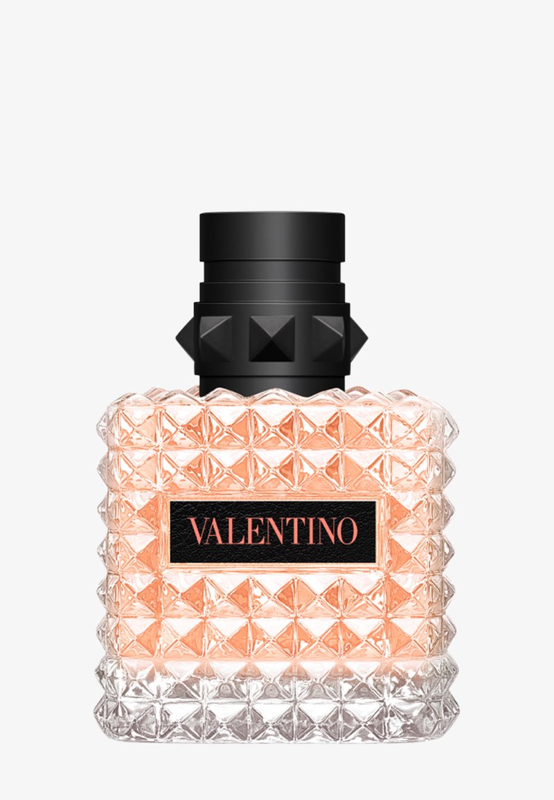 Vierkante glazen parfumfles met een gestructureerd ruitpatroon, lichtroze vloeistof binnenin, zwarte dop met studs en een zwart etiket met de tekst Valentino.