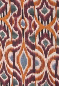 Tekstiil julge geomeetrilise mustriga, kus on oranži, lilla ja teali toone kreemival taustal, luues elava visuaalse tekstuuri.