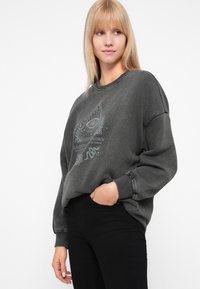 Donkergrijze sweatshirt met een losse pasvorm, voorzien van een grafisch ontwerp van een oog en zee-elementen in lichtblauw. Geribbelde manchetten en halslijn.