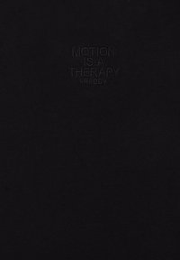 Camiseta de algodón negra con una etiqueta en relieve que dice "MOTION IS A THERAPY FREDDY." Textura suave, diseño minimalista.