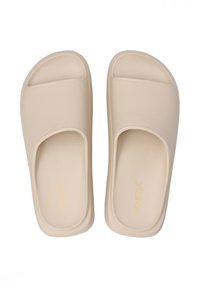 Beige slide-sandaler med åben tå-design, lavet af glat materiale; har en tekstureret fodseng og subtil branding på siden.