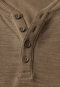 Brun, texturerad skjorta med henleykrage som har tre matchande knappar och en liten fickdetalj på vänster sida.