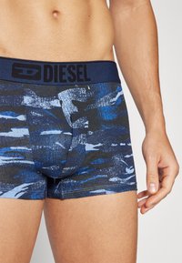 Boxers pour hommes à motifs bleu et marine avec une ceinture noire Diesel. Fabriqués dans un tissu doux et extensible, ils disposent d'un design ajusté.
