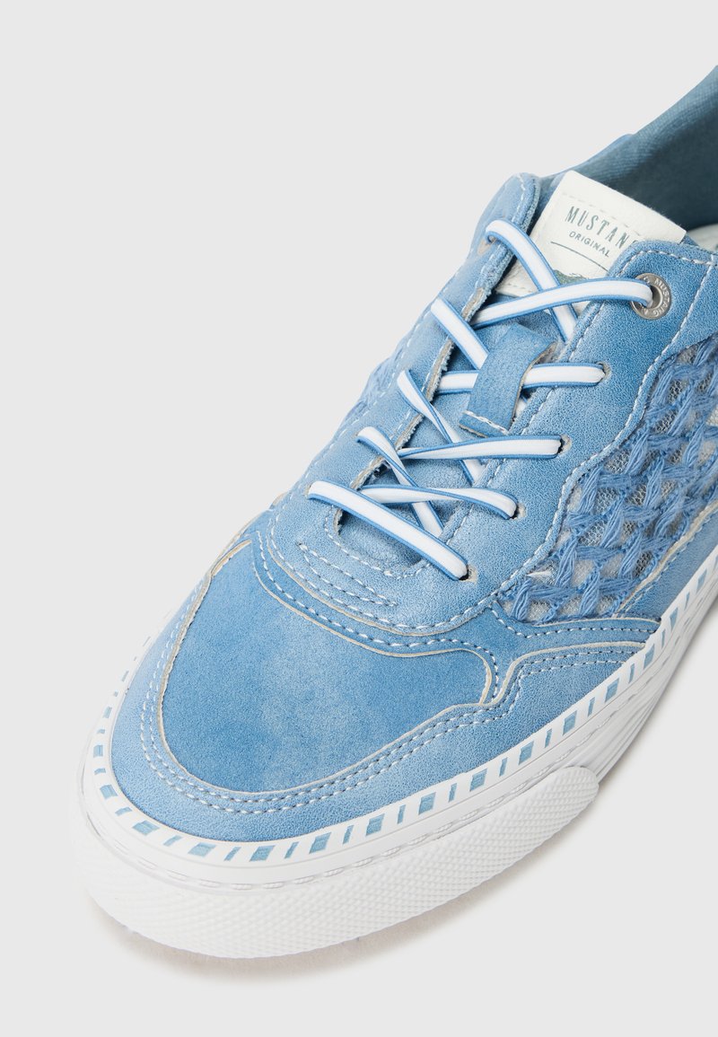 Zapatillas de ante azul claro con paneles laterales trenzados, suela de goma blanca y cordones azul claro. Presenta costuras en contraste y una etiqueta de marca.